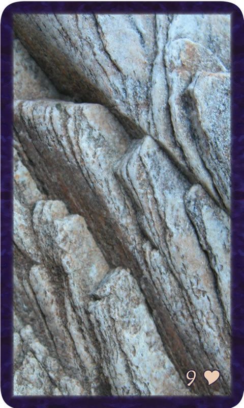 Macro photo of rising layers of stone. Gratitude Tarot card Nine of Kindness: held in this place, a tiny voice insists the view will clear in time.