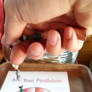 Hold your pendulum where it is comfortable and moves naturally. This may be with the "handle" nestled in the palm of your hand.