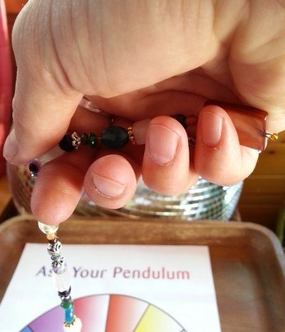 Hold your pendulum where it is comfortable and moves naturally. This may be with the "handle" nestled in the palm of your hand.